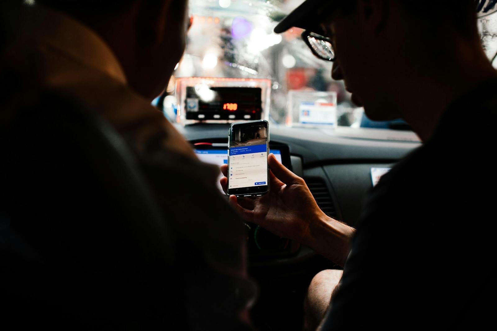 Two people using a smartphone for directions in a car at night.